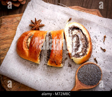 Gebackene Brötchen mit Mohn auf einem Holzbrett, Ansicht von oben Stockfoto