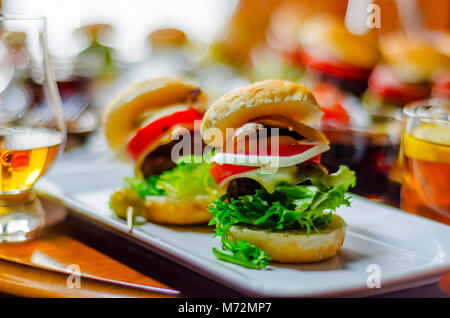 Mini Burger mit Fleisch, Gemüse, Käse und anderen Belag, Brot mit Sesam bestreut, mini Fast food, lecker einstellen Stockfoto