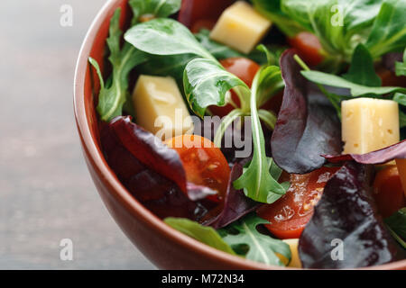 Makroaufnahme der Schüssel mit frischem Salat mit Tomaten, Käse und Blätter Mix aus Rucola, Radicchio, Frisee- und Feldsalat Stockfoto