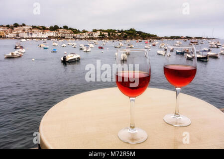 Zwei Gase von Rose auf dem Tisch, mit Hafen im Hintergrund, Cadaques, Alt Emporda Comarca, Costa Brava, Katalonien, Spanien Stockfoto