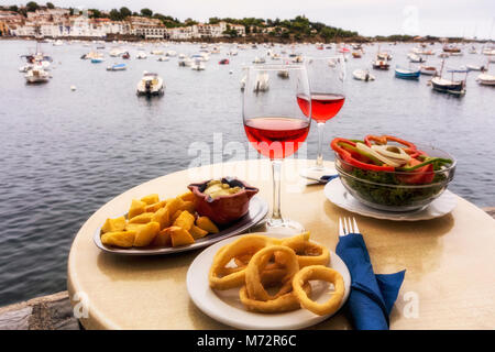 Zwei Gase von Rose und Tapas am Tisch, mit Hafen im Hintergrund, Cadaques, Alt Emporda Comarca, Costa Brava, Katalonien, Spanien Stockfoto