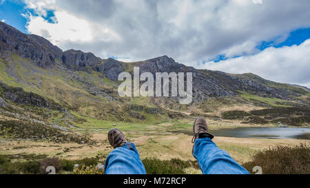 Wanderer, die sich auf der Bergseite mit Blick und Hiker's Stiefel - Unplugged Stockfoto