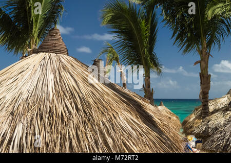 Einen strohgedeckten Palme Wedel palapa Dach am schönen Strand unter Palmen, in der sonnigen Karibik. Stockfoto