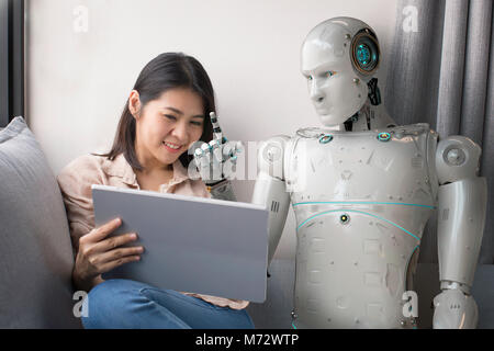 Asiatische Frau im Gespräch mit Roboter während der Verwendung digitaler Tablette zu Hause Stockfoto