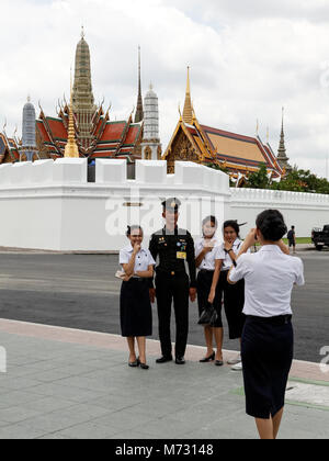 Mädchen mit einem thailändischen Armee Offizier mit dem Grand Palace in Bangkok im Hintergrund Stockfoto