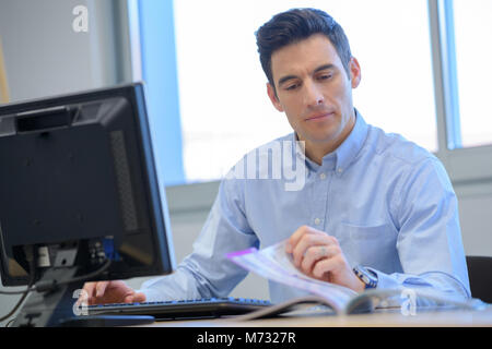 Geschäftsmann in einem Büro schauen durch einen Katalog Stockfoto