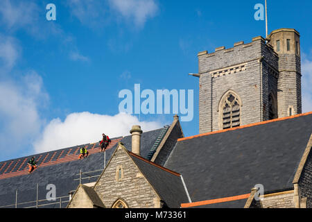 Zur Festsetzung der Dach, während die Sonne scheint. Das satteldach aller Heiligen Kirche in Barry, Wales auf einem hellen, sonnigen Tag unter einem blauen Himmel repariert wird Stockfoto