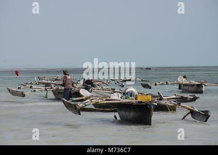 Dhow traditioneller Fischereifahrzeuge in Jambiani Hafen Zanzibar Tansania bei Ebbe mit einem Fischer drücken das Boot aufs Meer. Stockfoto