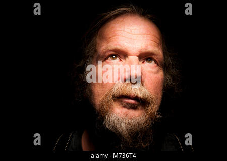 Close-up ein älterer Mann mit Bart vor schwarzem Hintergrund suchen Stockfoto