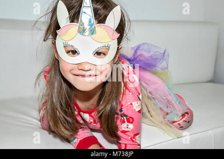 Ein sechs Jahre altes Mädchen mit einem Einhorn Maske Stockfoto