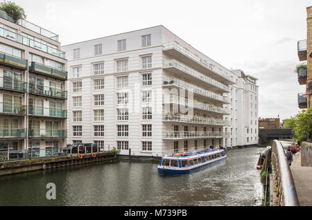 Ein Kanal tour Boot übergibt Gilbey Haus, auf der Regent's Canal. Es ist ein Apartment Block bei 38 Jamestown Road, Camden Town, London, UK. Stockfoto