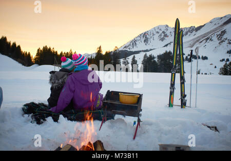 Ein romantisches Paar mit BBQ-Picknick im Schnee suchen bei Sonnenuntergang lifestyle urlaub momente Team Urlaub in den Schweizer Alpen Stockfoto