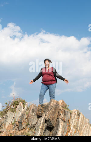 Eine asiatische Frau mit ihren Armen weit oben auf farbige Felsen Stockfoto