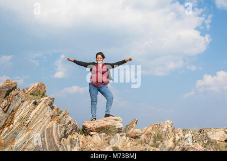 Eine asiatische Frau mit ihren Armen weit oben auf farbige Felsen Stockfoto