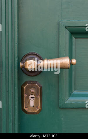 Goldene Türgriffe auf grünen Holztüren. Stockfoto