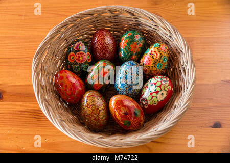 Ein Korb mit Holz- Eier, mit floralen Mustern auf einem Tisch gemalt, wie Ostern Dekoration. Stockfoto