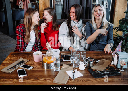 Vier Freunde im Cafe Blick in die Kamera und Lachen Stockfoto