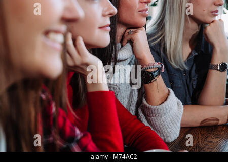 Seitenansicht eines Vier lächelnden Freunde saßen am Tisch im Cafe Stockfoto