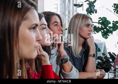 Seitenansicht eines Vier lächelnden Freunde saßen am Tisch im Cafe Stockfoto