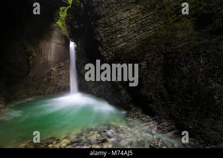 Versteckten Wasserfall Kozjak streams aus geschichteten, bemoosten Felsen in eine tiefe Schlucht, glasklaren Pool. Stockfoto