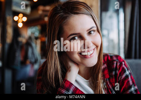 Schöne Brünette an Kamera im Cafe sitzen lächeln Stockfoto