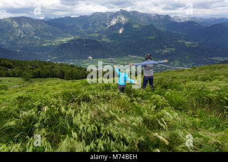 Mutter und Sohn stehen im hohen Gras steigende Hände auf die Wanderung zum matajur Berg an der Grenze zwischen Italien und Slowenien Stockfoto