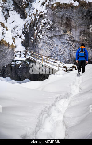 Menschen wandern durch tiefen Schnee zu Holztreppe in gefrorenen vereisten Schnee bedeckte Schlucht Baerenschuetzklamm im Winter in Österreich Stockfoto