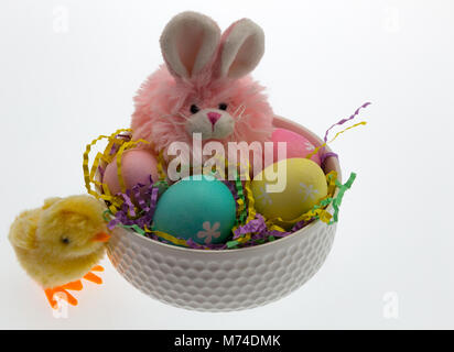 Rosa Osterhasen und mehrere Hand Eier in einer weißen Schüssel vermitteln ein Ostern Thema für Kinder gefärbt. Stockfoto