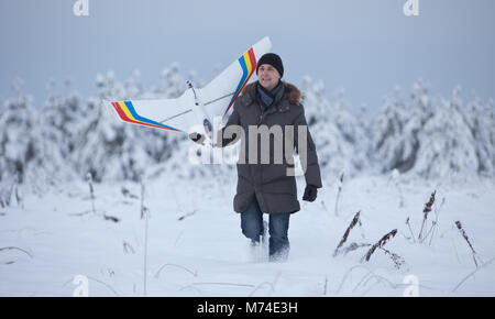 Glückliche Menschen gehen auf Schnee Winter mit rc-weißen Flugzeug Modell Stockfoto