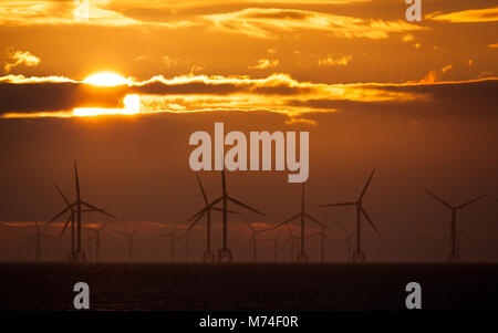 Sonnenuntergang über Windkraftanlagen in der Irischen See, Großbritannien Stockfoto