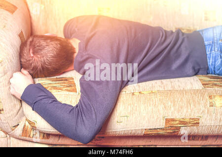 Ein Mann schläft auf dem Bauch auf dem Sofa. Der Mann ist Dösen Stockfoto