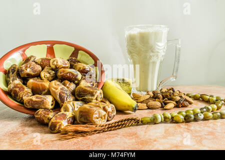 Ein frisches Glas Banane Milchshake mit vielen Terminen und Mandeln und eine religiöse Tasbeeh auf einem Marmortisch gehalten und bereit iftar im Heiligen m zu öffnen. Stockfoto