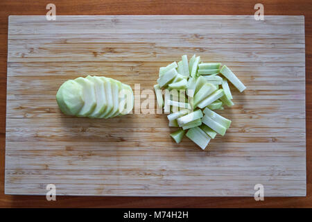 Kohlrabi schälen und in Scheiben geschnitten auf einer Vintage Bambus Schneidebrett Stockfoto
