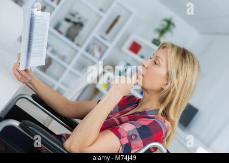 Frau im Rollstuhl mit Fotoalbum zu Hause Stockfoto