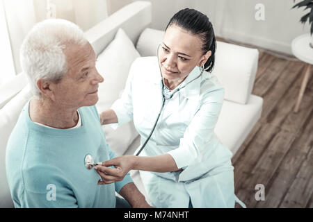 Nette erfahrene Krankenschwester sitzen und die Prüfung ihrer Patienten. Stockfoto