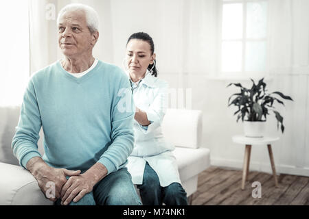 Alter grauhaariger Mann sitzt mit dem Rücken zum Arzt. Stockfoto