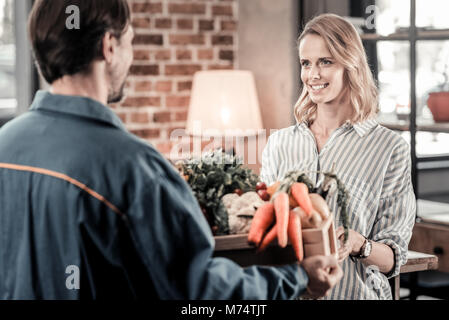 Glückliche junge Frau an der Delivery Man suchen Stockfoto