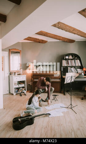 Süße kleine Mädchen mit Gitarre Lehrer im Zimmer Stockfoto