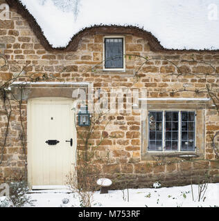 Reetgedeckte Ferienhaus aus Stein im Winter Schnee. Große Tew, Cotswolds, Oxfordshire, England Stockfoto