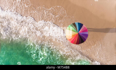 Bunte Sonnenschirm am Strand und Schaum von sea wave von oben Blick Foto im Sonnenlicht leuchten. Stockfoto