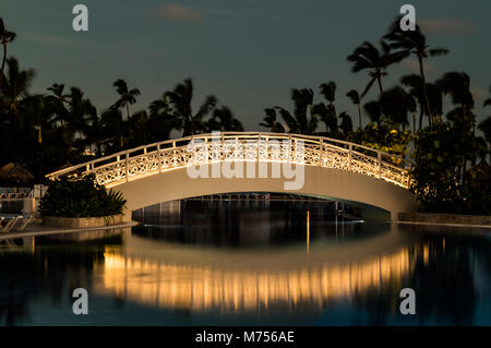 Lange Belichtung einer beleuchteten Fuß Brücke über einen Pool als dawn Breaks. Stockfoto