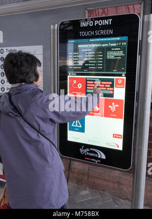 Frau mit Info Point Touchscreen Display auf Berwick upon Tweed Bahnhof, Northumberland, England, Großbritannien Stockfoto