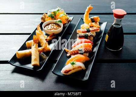 Verschiedene Arten von Sushi serviert auf schwarzem Stein Stockfoto