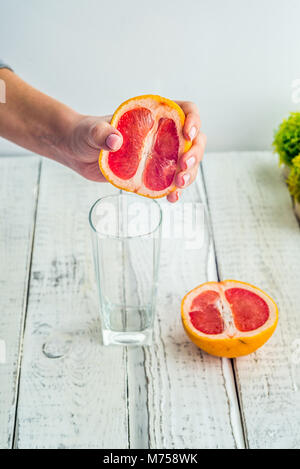 Frisch gepresster Grapefruitsaft in Glas Glas Fougères in die Hände eines Mädchens mit schöne Nägel und Maniküre, gesunden Lebensstil Stockfoto