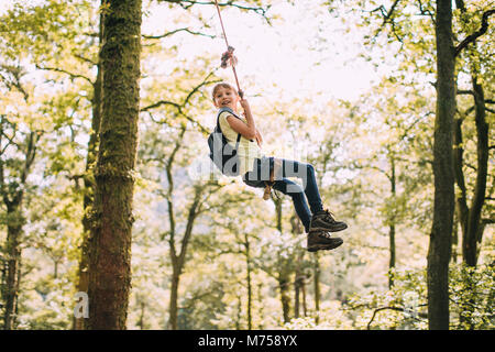 Kleine Junge ist sich auf eine Schaukel, die er gefunden hat, beim Wandern. Stockfoto