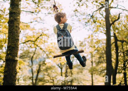 Kleine Junge ist sich auf eine Schaukel, die er gefunden hat, beim Wandern. Stockfoto