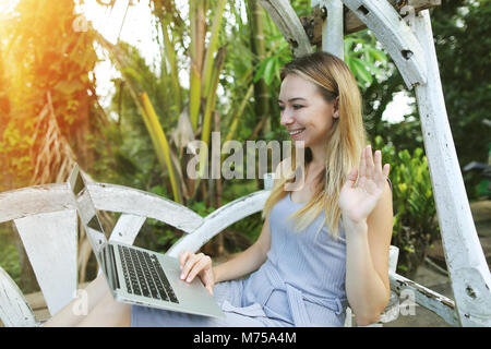 Blonde Frau mit Laptop für die Arbeit an einem sonnigen Tag, Hintergrund Sonnenschein grüne Palmen in Thailand, Phuket reisen Stockfoto