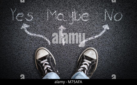 Ein Teenager in Jeans und Canvas Schuhe stehen auf Asphalt mit einer Auswahl von Ja, Vielleicht, nein Konzept der ständigen an der Kreuzung nicht in der Lage einen de Stockfoto