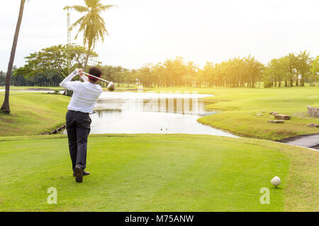 Junge asiatische Geschäftsmann spielen Golf auf dem wunderschönen Golfplatz am Morgen mit Sunbeam im Sommer. Stockfoto