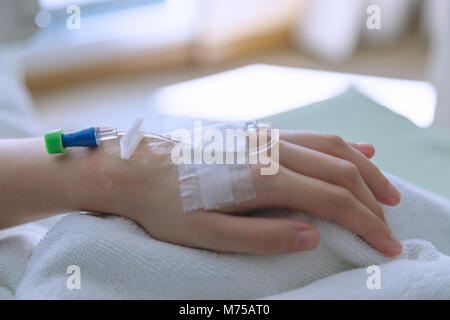 Kochsalzlösung Rohr an Hand der Frau Patienten im Zimmer des Patienten nach der Operation im Krankenhaus. Versicherung und medizinische Konzept. Stockfoto